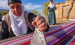 Evinin bahçesindeki tezgahta asırlık yöntemle kilim dokuyor