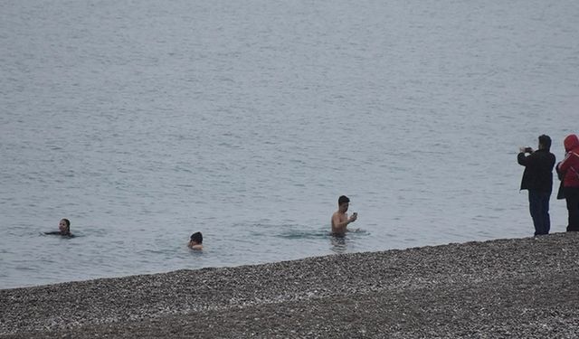 Antalya'da bazı kent sakinleri ve turistler yağışa rağmen denize girdi